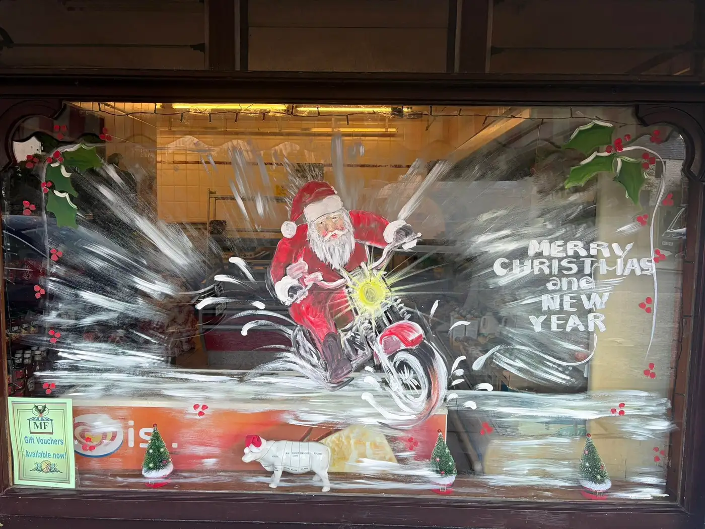 The shop window hand-painted for Christmas with Santa on a motorbike and an MF Gift Vouchers sign